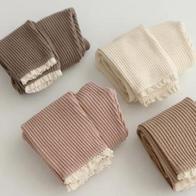 Quatro leggings de malha canelada com barra em renda, em vários tons castanhos e bege sobre fundo claro
