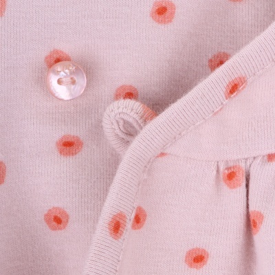 tecido rosa claro com padrão de círculos laranja e botão transparente