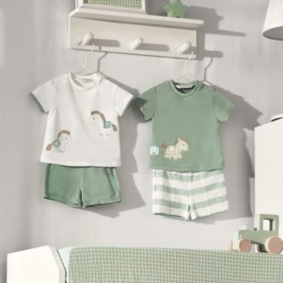 Dois conjuntos de roupa de bebê pendurados numa prateleira branca numa parede cinzenta