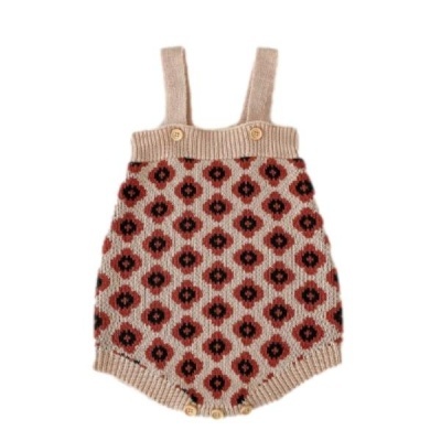 Macacão de bebé em malha bege com padrão de losangos castanhos e pretos, com botões nas alças e na zona inferior.