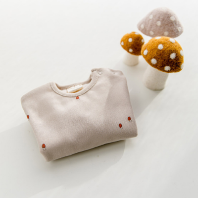 Sweat bege clara com padrões de cogumelos vermelhos e cogumelos de feltro decorativos ao lado