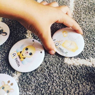 Dois botões infantis com ilustrações de abelha e queijo e texto em português