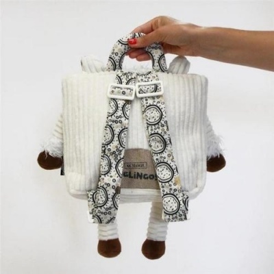 Mochila felpuda branca com alças estampadas e detalhes castanhos, semelhante a ovelha, segurada por uma mão