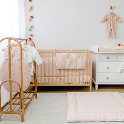 Quarto de bebé com berço, muda-fraldas, tapete e estendal com roupa
