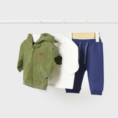 Conjunto de roupa infantil com casaco verde, camisola branca e calças azuis pendurado
