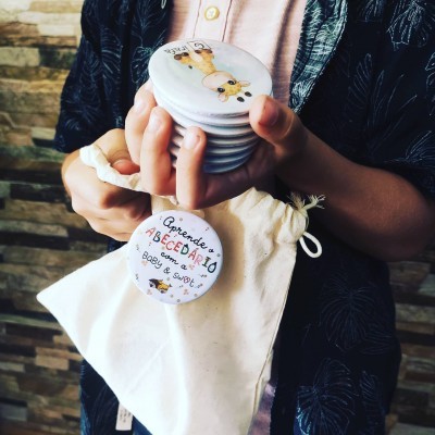 Criança segurando botons de aprendizagem do alfabeto e saco de algodão.