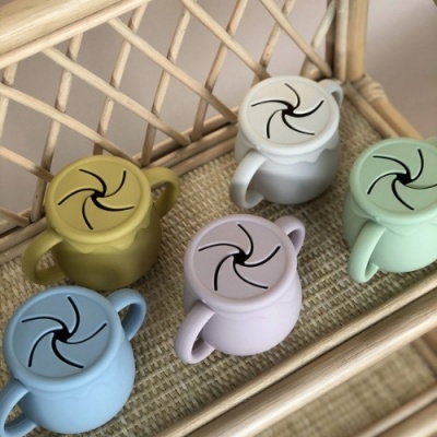 Copos de plástico coloridos com tampas ealças duplas numa bandeja de vime.