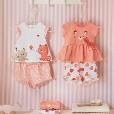 Dois conjuntos de roupa de bebé pendurados com padrões de animais e corações em fundo riscado rosa