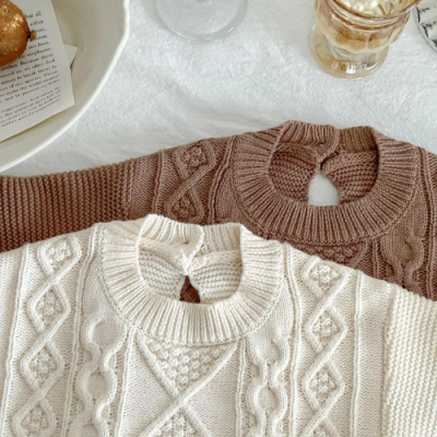 Casacos de malha creme e castanho claro com abertura e botão na gola, sobre tecido branco