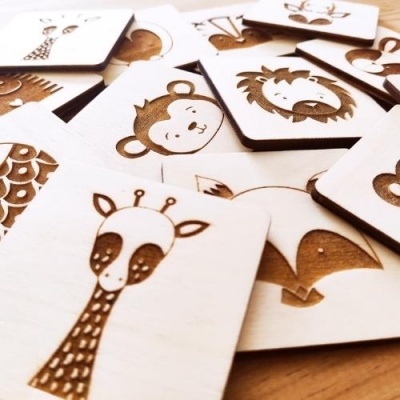 Cartões de madeira com desenhos gravados de animais sobre mesa de madeira.