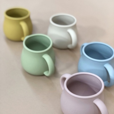 Cinco canecas de cerâmica coloridas e arredondadas sobre superfície bege