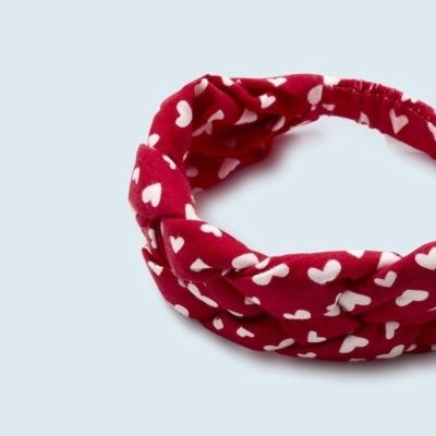 Faixa de cabelo vermelha com corações brancos sobre fundo azul claro