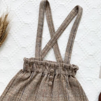 Jardineira risca de giz castanha com alças cruzadas sobre fundo branco