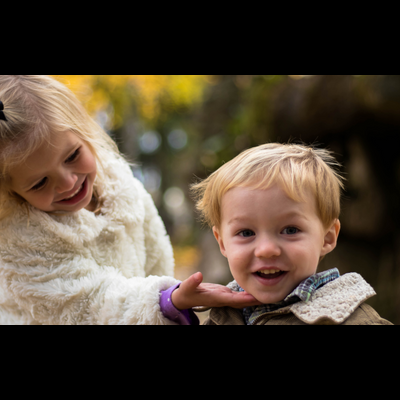 Duas crianças sorridentes em ambiente natural de outono.