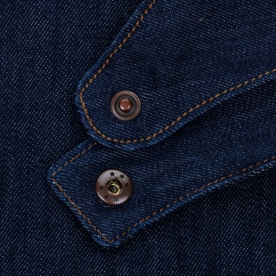 Close-up de tecido de ganga azul escuro com costura castanha e botões metálicos