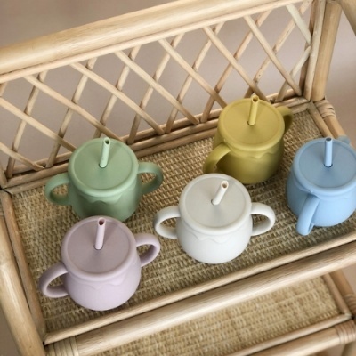 Cinco copos coloridos com tampa e canudo em prateleira de bambu