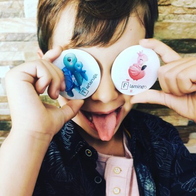 Criança com bottons de tartaruga e flamingo sobre os olhos