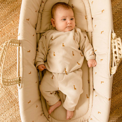 Bebé deitado em berço portátil bege com padrão de girafas