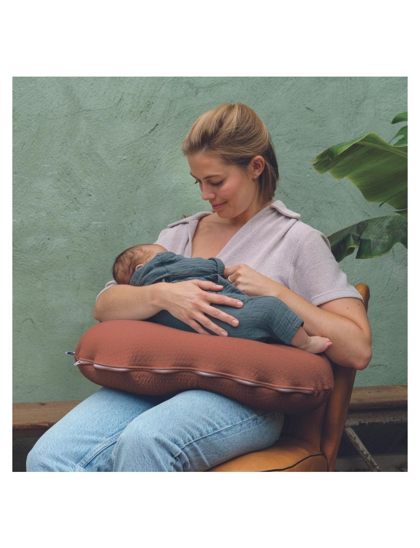 Mulher segurando bebé com almofada castanha à volta da cintura