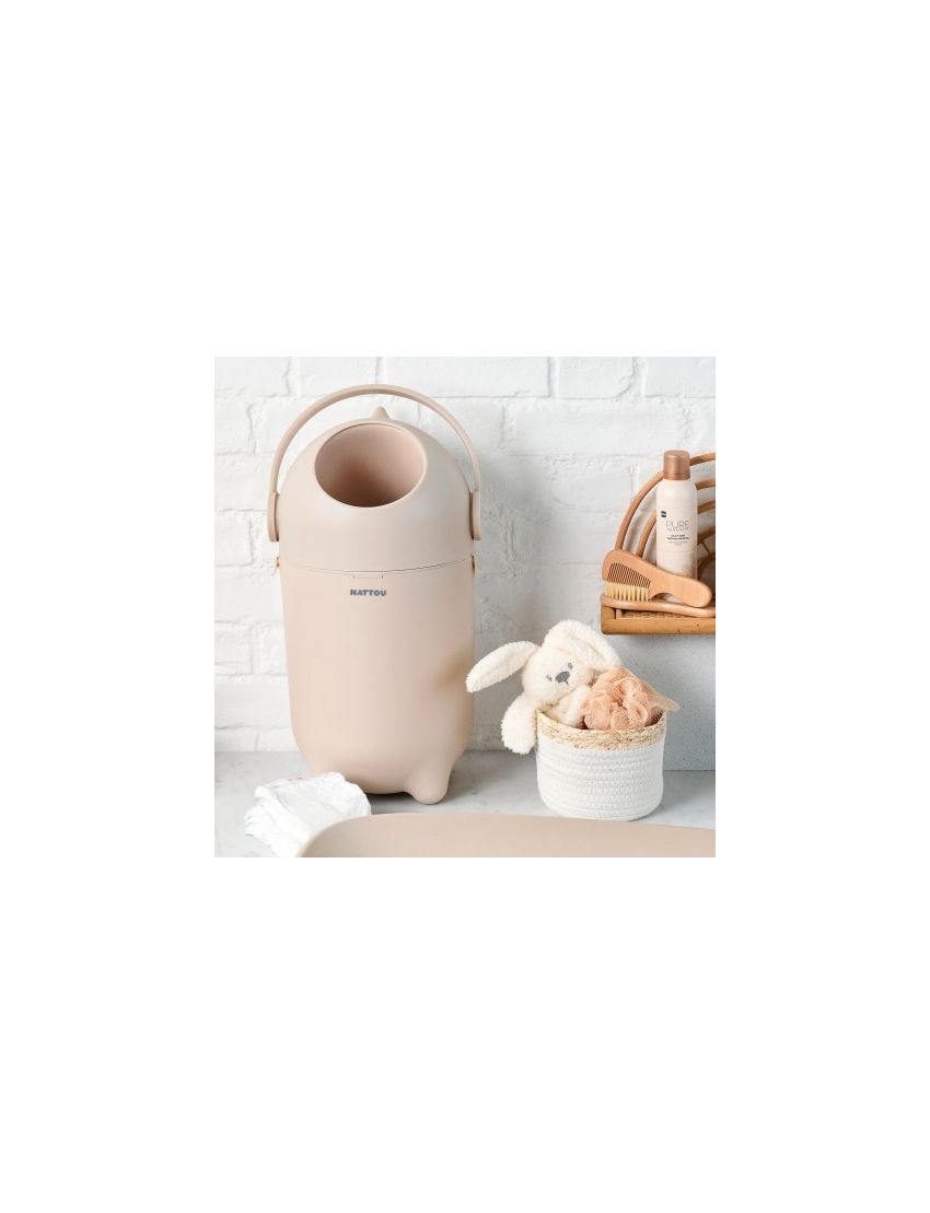 Contentor de fraldas bege com pega e texto MATTOU numa bancada com itens de bebé