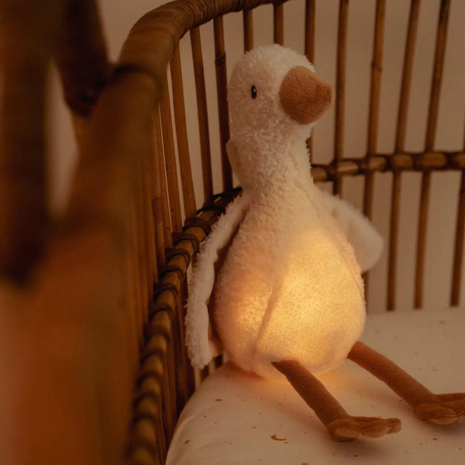 Pelúcia de pato com luz dentro sentada em berço de madeira