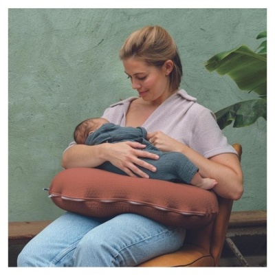 Mulher segurando bebé com almofada castanha à volta da cintura