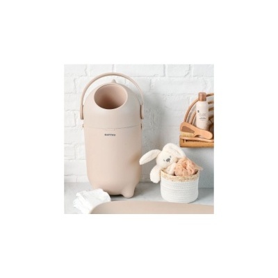 Contentor de fraldas bege com pega e texto MATTOU numa bancada com itens de bebé