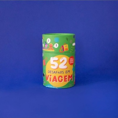 Embalagem cilíndrica verde com texto '52 Desafios em Viagem' e ilustrações coloridas