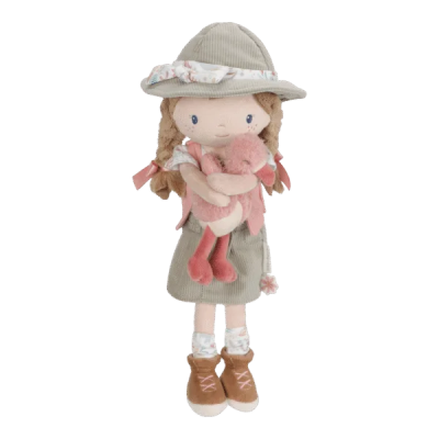 Boneca de pano com chapéu, saia e mochila bege segurando um flamingo cor-de-rosa de peluche