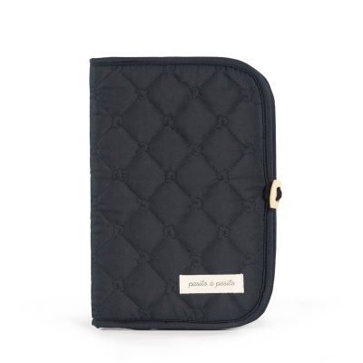 Capa acolchoada preta com padrão de losangos e etiqueta pasito a pasito.
