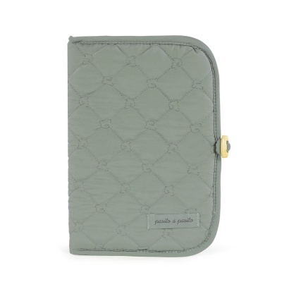 Capa acolchoada verde com padrão em losangos e etiqueta pasito a pasito.