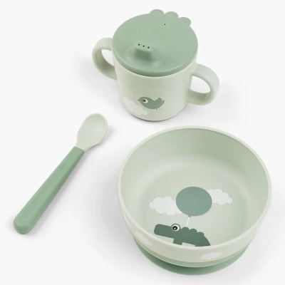 Conjunto infantil com caneca verde clara com tampa e bico, colher verde e taça verde com desenho de crocodilo e balão.