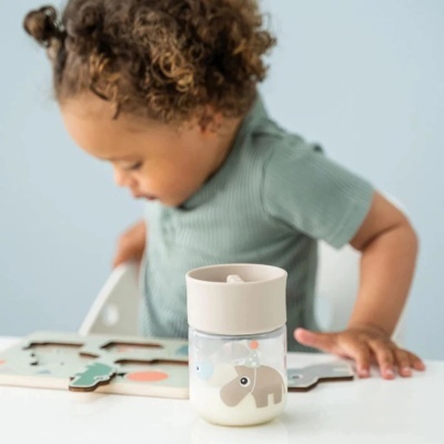 Garrafinha para bebé com tampa bege e desenho de hipopótamo ao fundo criança a brincar com puzzle.