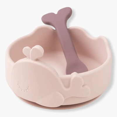 Taça de silicone rosa com design de baleia e colher roxa.