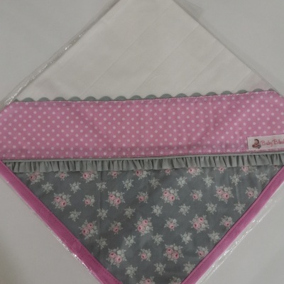 Toalha de bebé branca com bordas cor-de-rosa e cinzenta com padrões florais e bolinhas.