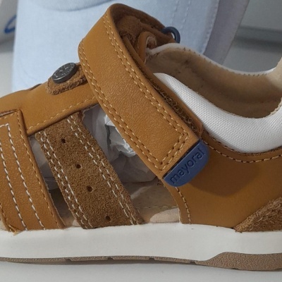 Sandália castanha de criança com fecho de velcro azul e sola branca.