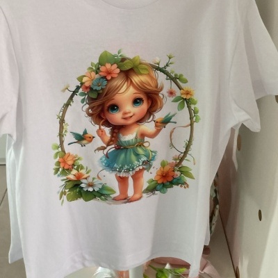 T-shirt branca com estampa de boneca, flores e pássaros, pendurada em cabide