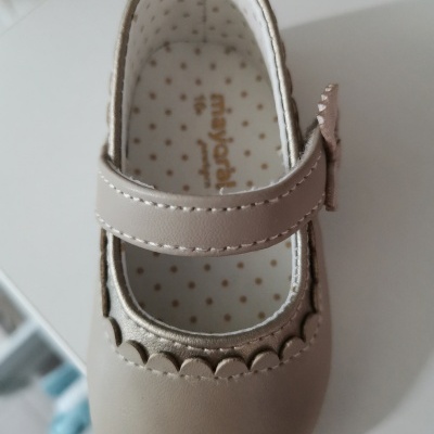 sapato infantil feminino bege com tirante e laço em superfície branca