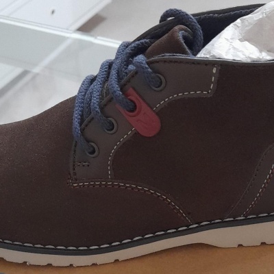 Bota castanha escura de camurça com atacadores azuis em cima de caixa