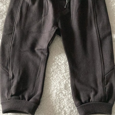 Calças de treino para criança pretas com cintura elástica e cordão cinzento.