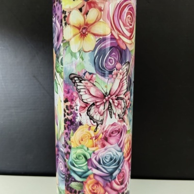 Copo térmico com padrão colorido de flores e borboleta, fundo preto.