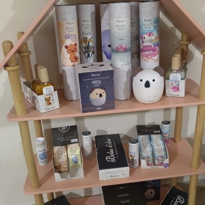 Expositor rosa com produtos de beleza como óleos essenciais e difusores em embalagens com desenhos de ursinhos e flores