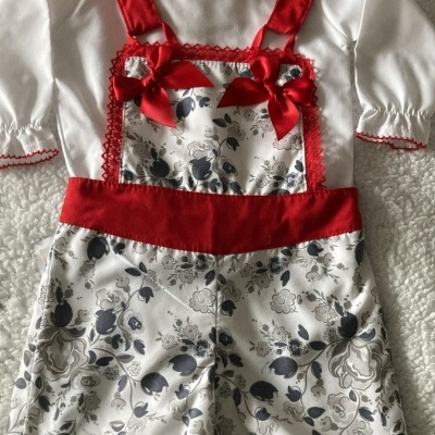 Roupa de bebé branca e vermelha com padrão floral cinza