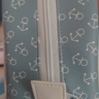 Estojo azul com padrão de âncoras brancas e fecho de correr branco.