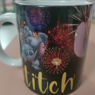 Caneca preta com desenho de Stitch, fogos de artifício e texto amarelo