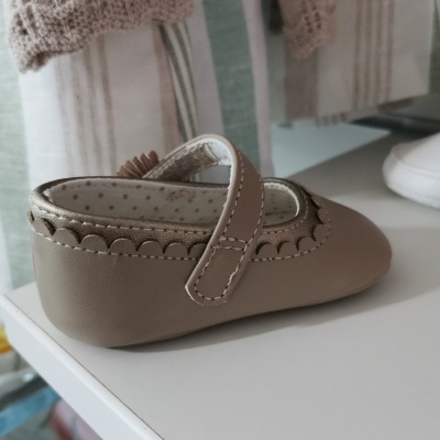 Sapatinho de bebé castanho claro com fecho de velcro e interior forrado manchado de pontos castanhos