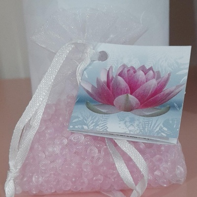 Saquinho branco com esferas rosas e etiqueta de flor de lótus