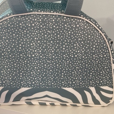 Mala de mão cinza com padrão de pontos brancos e riscas de zebra preto e branco