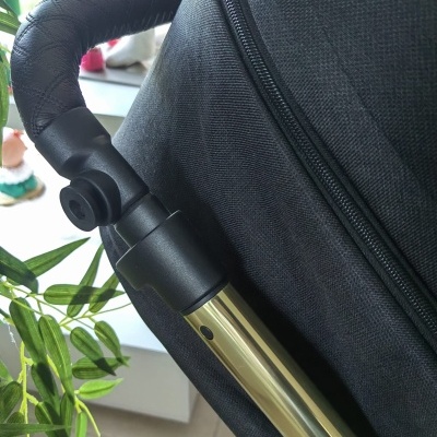 Parte de carrinho de bebé preto com estrutura dourada e alça acolchoada