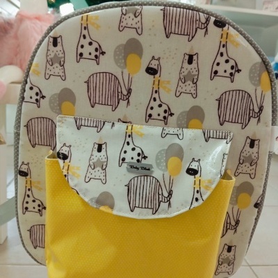 mochila infantil com padrão de animais e bolso amarelo numa loja decorada para Natal